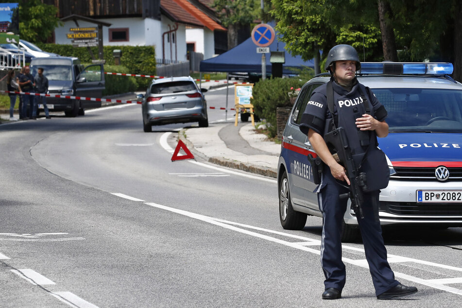 Ein bewaffneter Polizist sichert einen Straßenabschnitt am Tatort einer Tötung.
