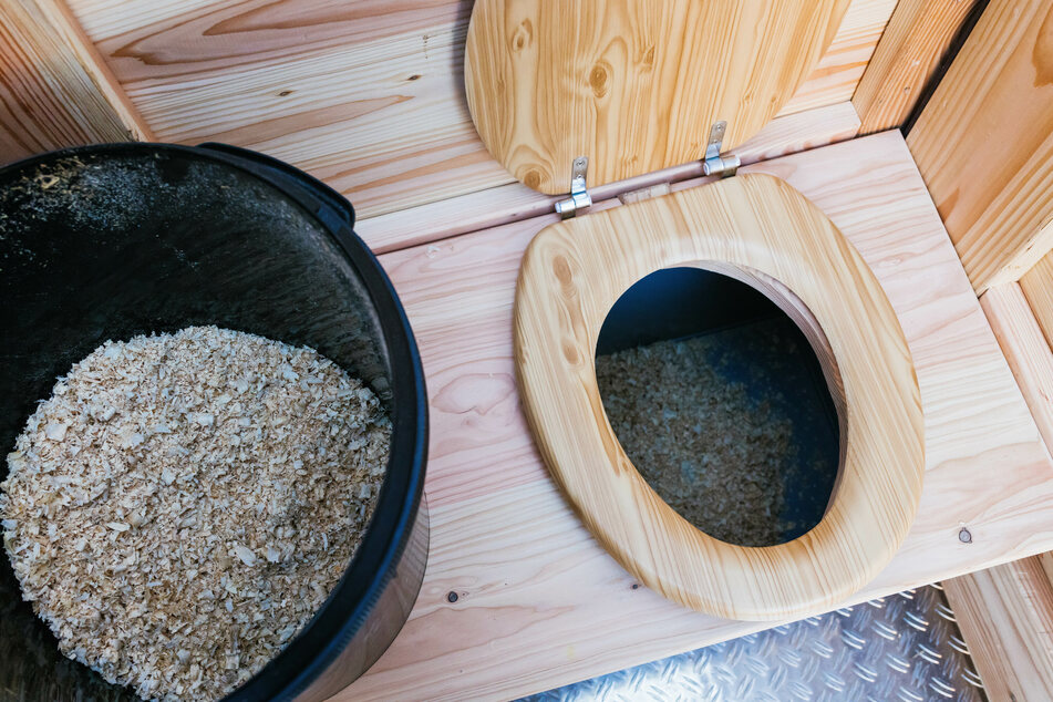 Holzspäne liegen in einem Eimer, von dem aus sie nach erfolgtem "Geschäft" in den Behälter unter dem WC-Sitz geschaufelt werden sollen.