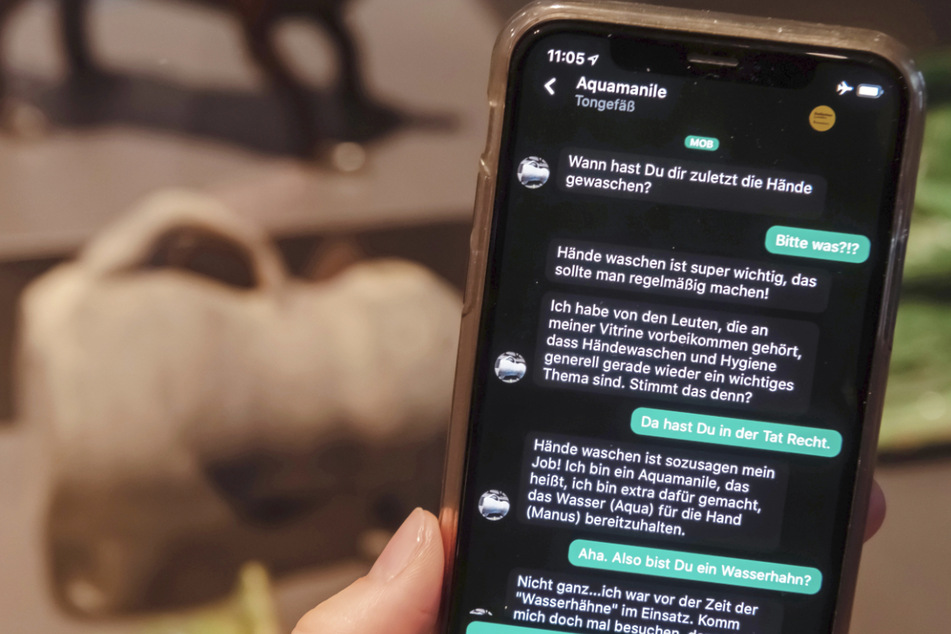 Im Badischen Landesmuseum wird vor einer Aquamanile aus dem Spätmittelalter auf einem Smartphone eine App gezeigt, mit der Museumsbesucher Kontakt zu Ausstellungsobjekten aufbauen können.
