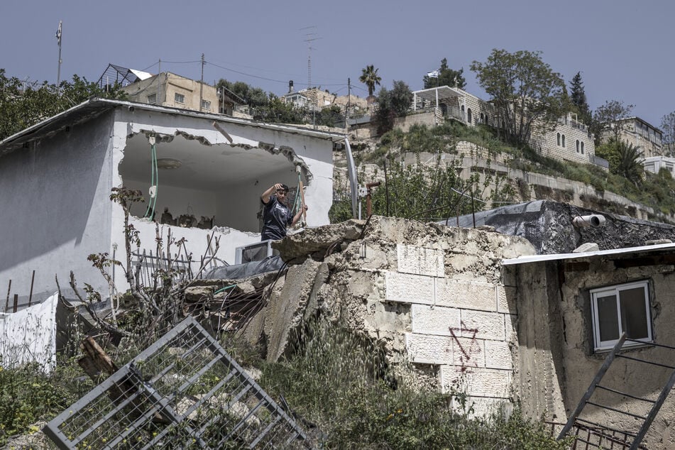 A Star of David is daubed on a wall as Ouday, the 13-year-old nephew of Omar Abu Rajab (not seen), prepares to discard a piece of furniture from his uncle's home, which he and other family members are helping to demolish, in Silwan on April 16, 2026.