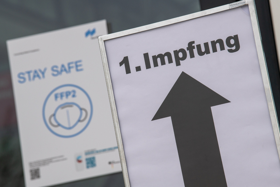 Ein Schild auf dem Gelände der Messe München zeigt im Eingangsbereich den Weg zur ersten Impfung an.