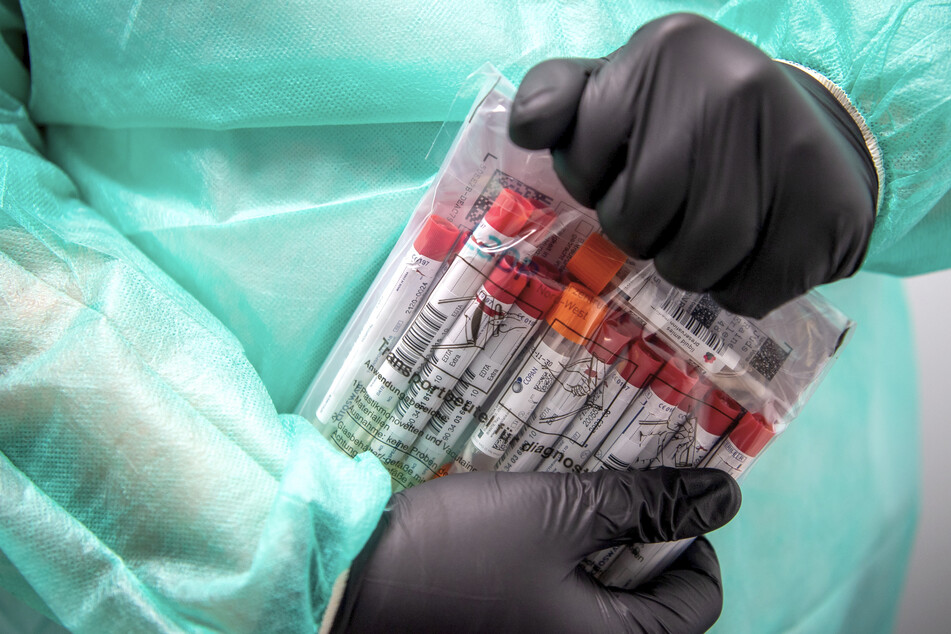 Proben für einen PCR-Test werden von einem Mitarbeiter im Corona-Testzentrum verpackt.