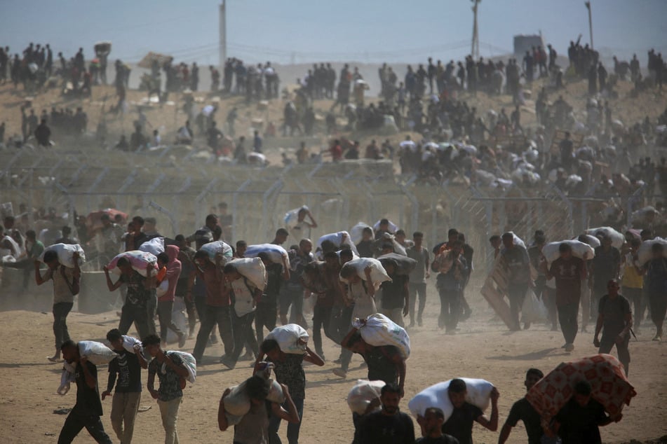 Palestinians carry aid supplies which they received from the Gaza Humanitarian Foundation in the central Gaza Strip on August 4, 2025.