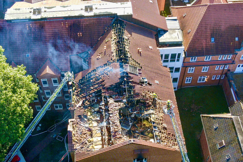 Feuerwehrleute sind nach dem Ausbruch eines Feuers im Klinikum im Einsatz am abgebrannten Dachstuhl.