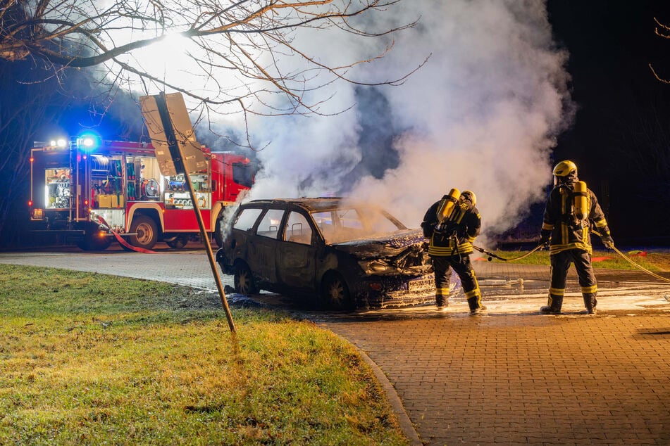 Die Feuerwehr bekämpft ein in Brand stehendes Auto auf einem Besucherparkplatz in Ostritz.