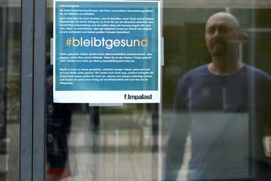 Ein Mann liest ein Hinweisschild vor dem geschlossenen Filmpalast unter dem Hashtag #bleibt gesund. Auch die meisten Kinos in Hessen bleiben geschlossen.
