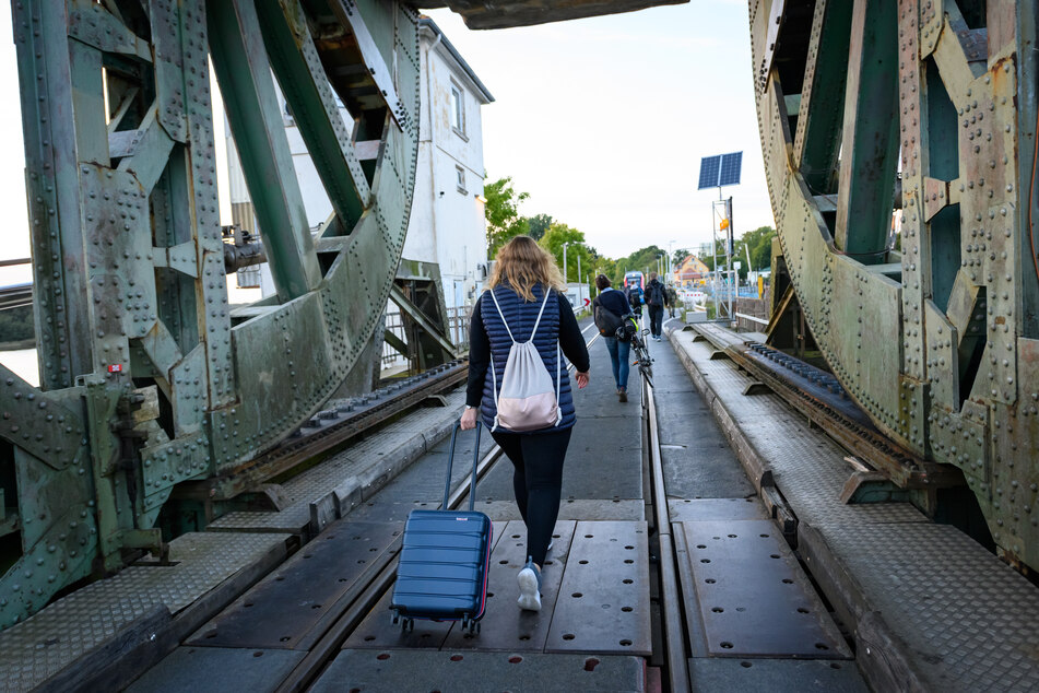 Eine Frau läuft mit einem Koffer über die Lindaunisbrücke. Seit Mitte September heißt es für Fahrgäste: aussteigen und zu Fuß die Schlei passieren.