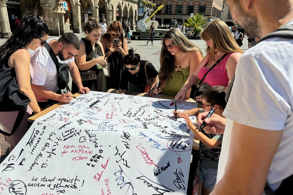 Menschen nehmen am Münchner Marienplatz an der Unterschriftenaktion teil.