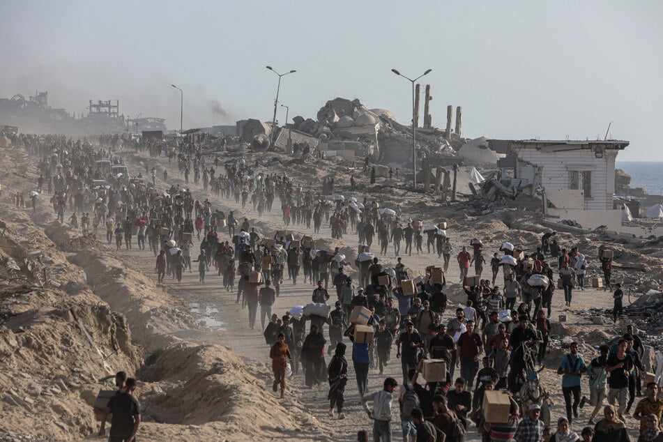 Palästinenser tragen Lebensmittelpakete, die von der The Gaza Humanitarian Foundation (GHF) verteilt wurden.