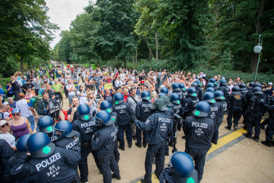 Polizisten drängen bei einem Protest gegen die Corona-Maßnahmen an der Siegessäule Menschen in den Tiergarten ab.