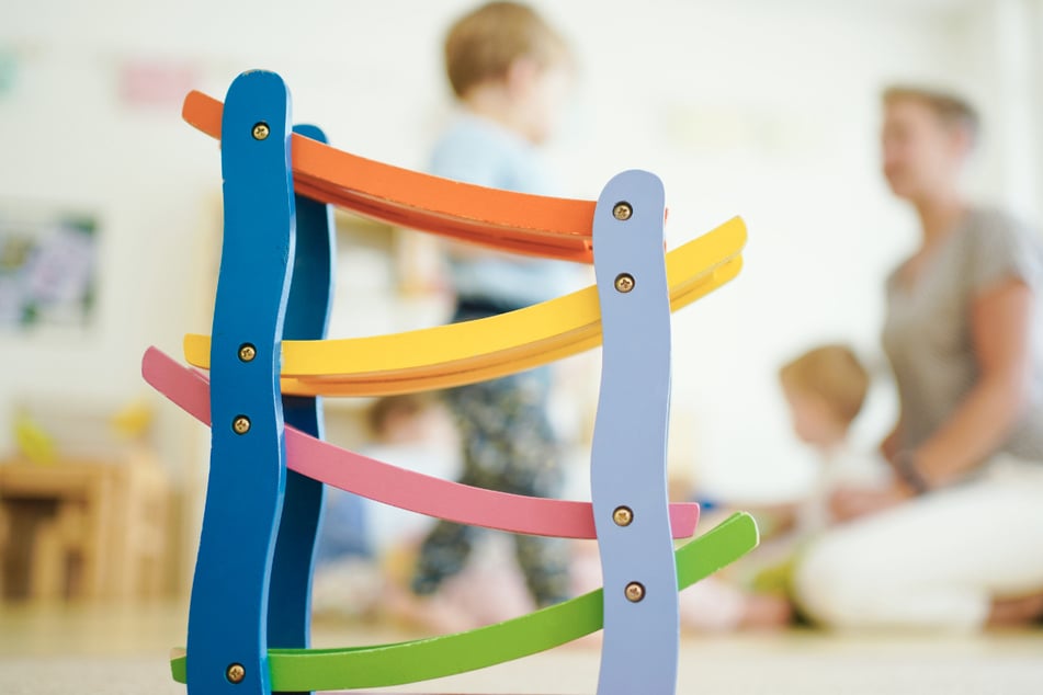 Eine Erzieherin spielt in einer Kindertagesstätte hinter einer Rollbahn mit Kindern. Im Landkreis Böblingen werden jetzt drei Wochen lang regelmäßig Hunderte von Jungen und Mädchen auf das Coronavirus getestet. (Symbolbild)