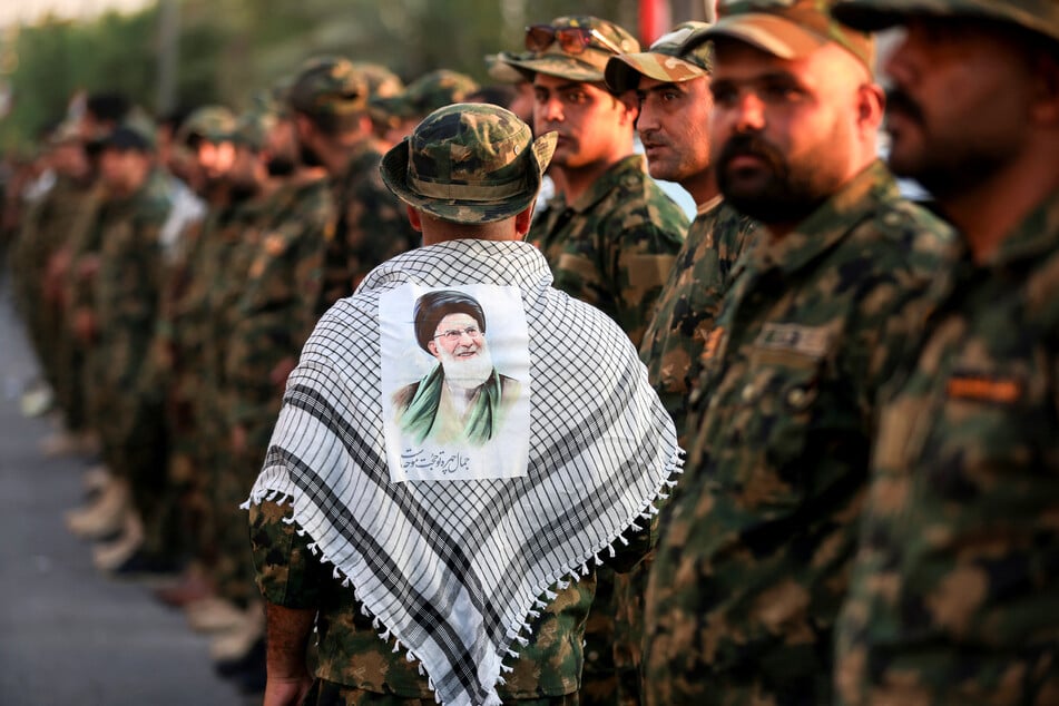 A member of Iraq's Popular Mobilization Forces wears a keffiyeh with a portrait of Iran's slain supreme leader Ali Khamenei ahead of security checks at the shrine of Imam Hussein on the eve of his funeral ceremonies in the holy Iraqi city of Karbala on July 7, 2026.