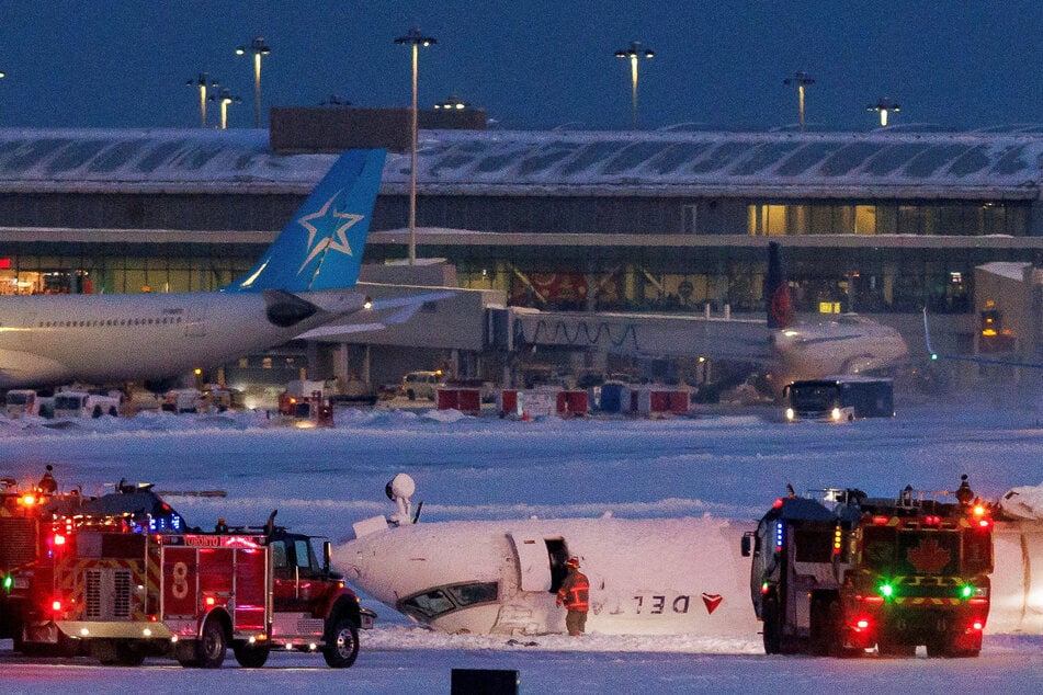 Emergency responders operate around a plane on a runway after a plane crash at Toronto Pearson International Airport in Mississauga, Ontario, Canada.