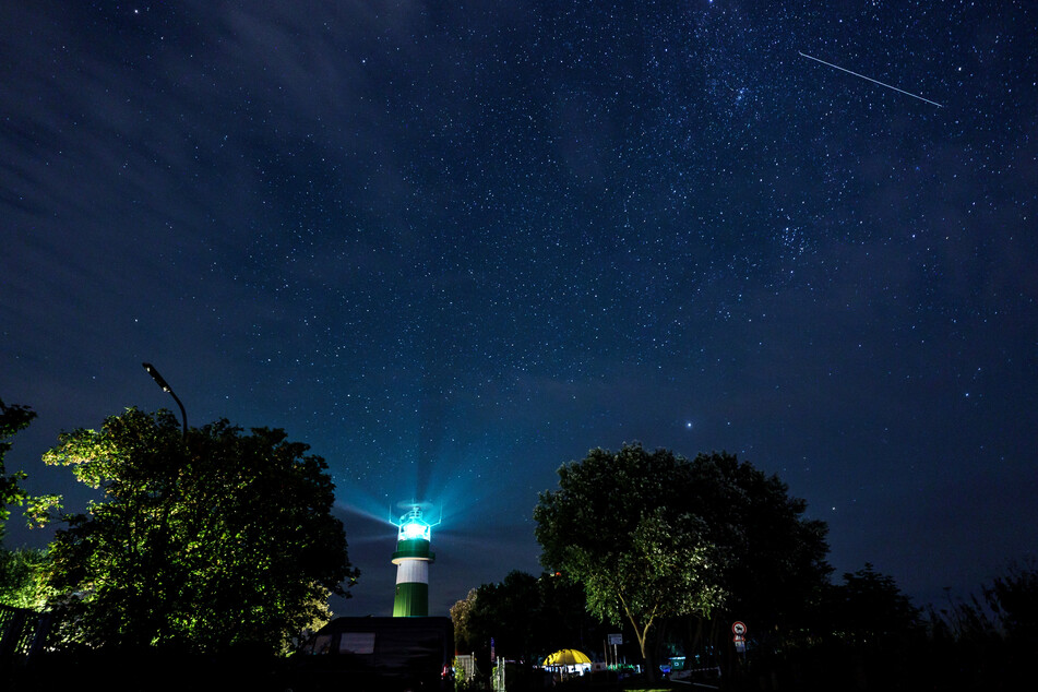 Eine Sternschnuppe zieht über dem Leuchtturm Bülk in Stade am Ufer der Ostsee ihre Bahn. Die Sternschnuppen der Perseiden sind in der ersten Augusthälfte teils im Minutentakt am Nachthimmel zu sehen.
