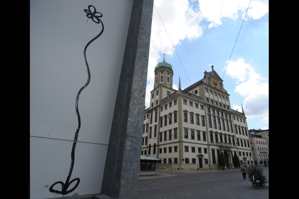 Neben dem Rathaus von Augsburg ist eine Graffiti-Blume zu sehen. Die Augsburgblume wurde überregional bekannt. Der Graffitikünstler muss sich nun am 19.11.2020 erneut wegen Sachbeschädigung durch Graffitis vor Gericht verantworten.