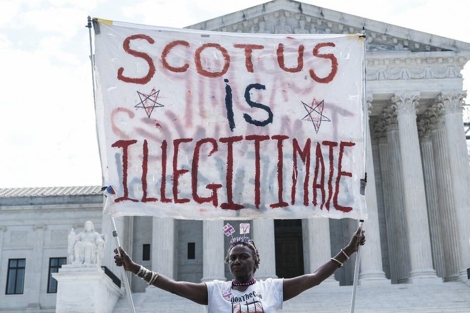 A demonstrator holds a "SCOTUS Is Illegitimate" banner outside the Supreme Court in Washington DC.