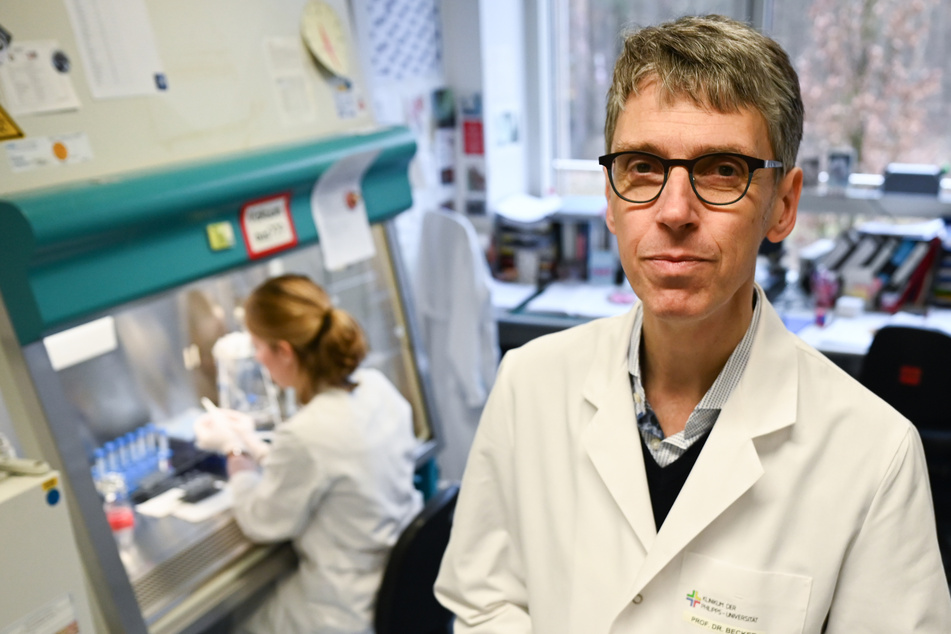 Professor Stephan Becker (61, r), Direktor des Instituts für Virologie der Philipps-Universität Marburg, steht in einem Forschungslabor neben einer Sterilwerkbank.