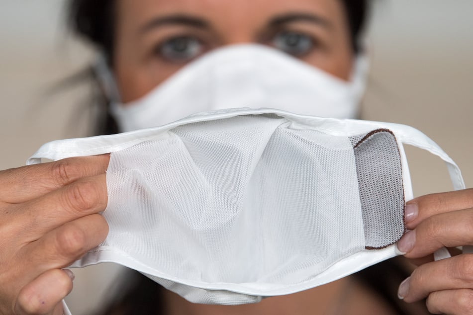 Jana Seidel, Mitarbeiterin des Automobilzulieferers C.H. Müller GmbH, demonstriert die Nutzung einer Mehrweg-Maske mit einem kupferhaltigen Filter.