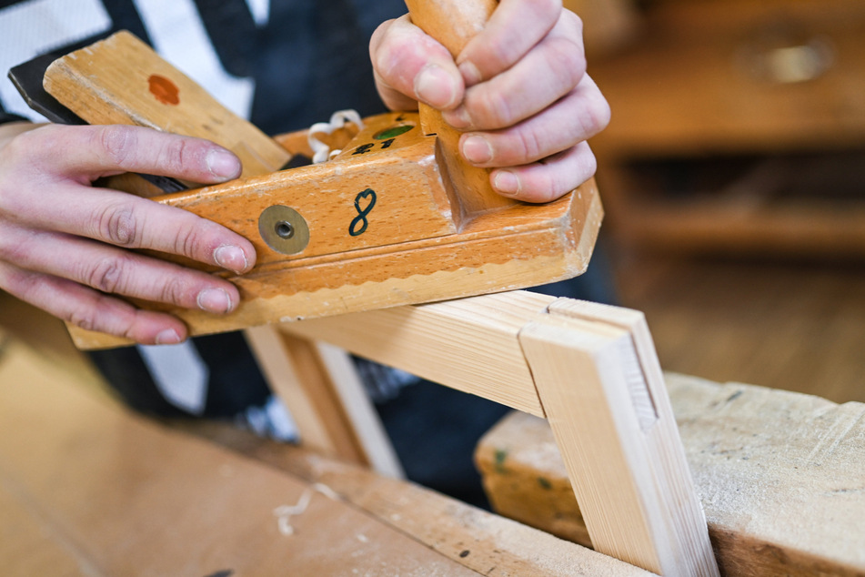 Ein Auszubildender im Schreiner-Handwerk arbeitet an einem Werkstück (Archivbild).