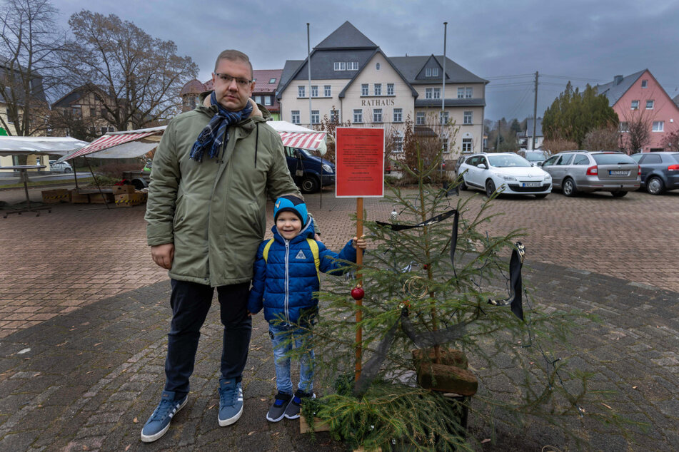 Sebastian Bräuer (31) und Sohn Niklas (4) mit dem traurigen Ersatzbäumchen vor dem Rathaus Pockau.