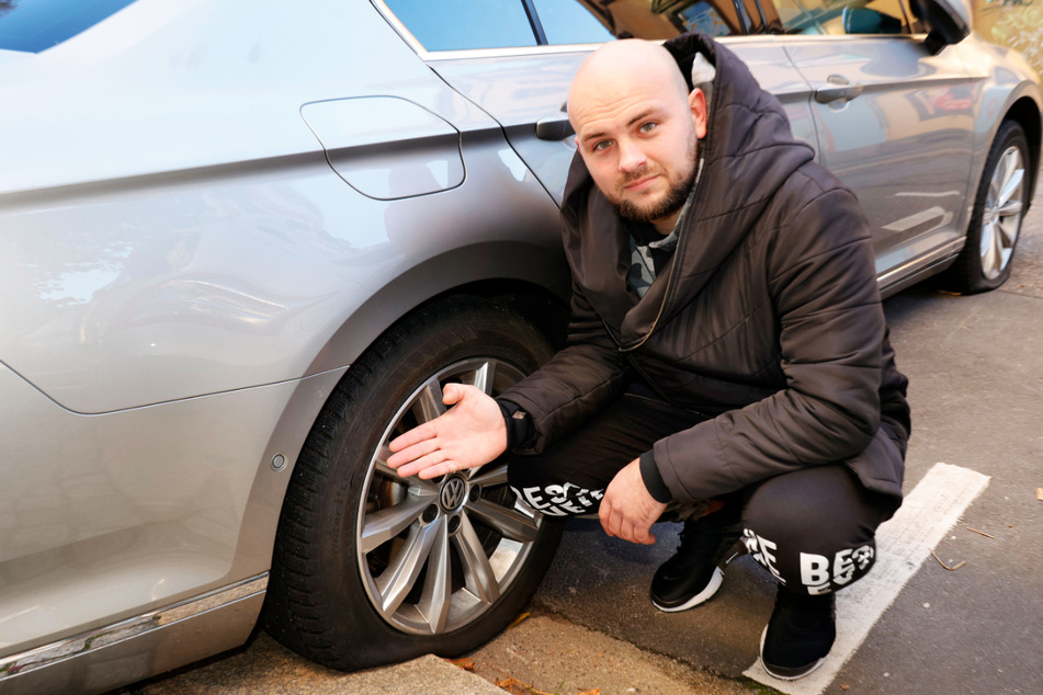Mykola Lyulko (32) zeigt auf die zerstochenen Reifen seines VWs.