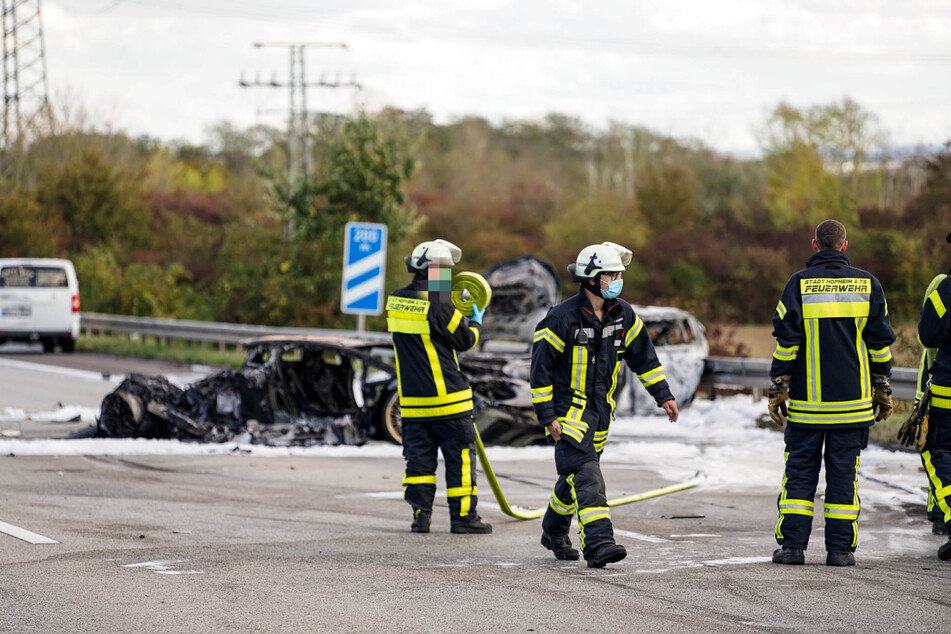 Einsatzkräfte der Feuerwehr Hofheim am Taunus stehen vor dem völlig ausgebrannten Lamborghini.