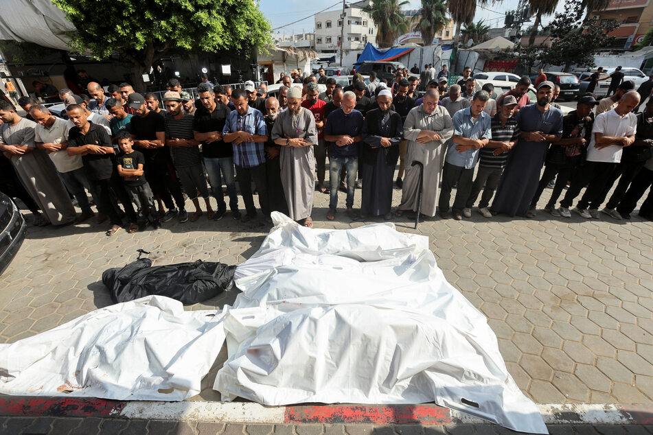 People pray near the bodies of Palestinians killed in Israeli strikes at Al-Aqsa Martyrs Hospital in the Gaza Strip's Deir Al-Balah.