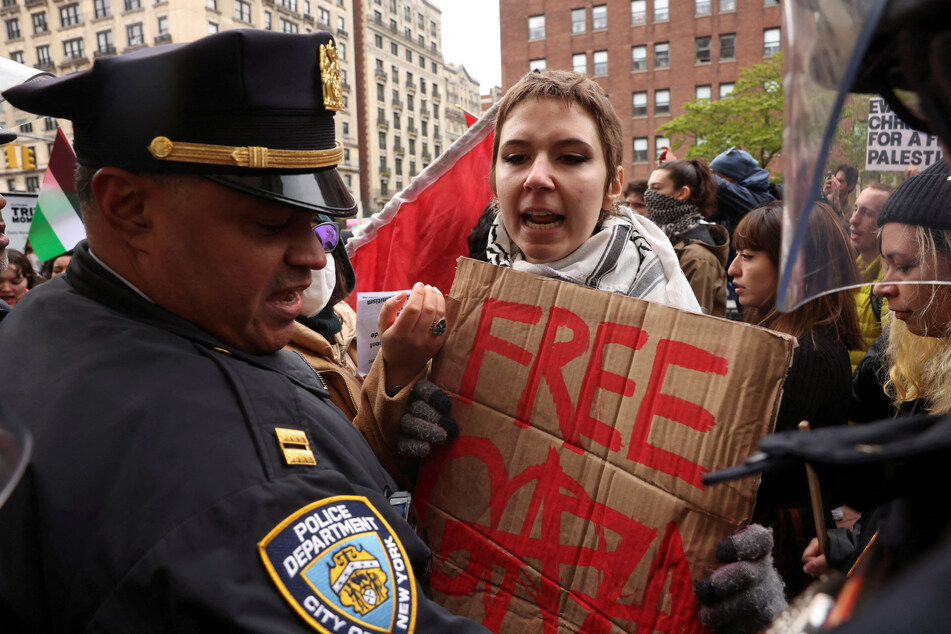 A demonstrator holds a sign reading "Free Gaza" near a police officer during a protest in solidarity with Pro-Palestinian organizers on the Columbia University campus.