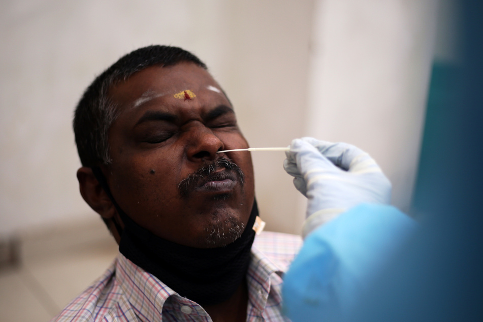 Medizinisches Personal nimmt von einem Mann eine Tupferprobe für einen RT-PCR-Test in Indien.