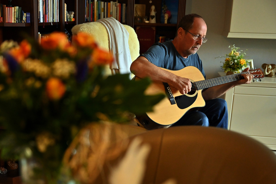 Roman Bialas sitzt in seinem Wohnzimmer und spielt auf der Gitarre. Es ist ein halbes Jahr her, dass er schwer an Covid-19 erkrankt ist.