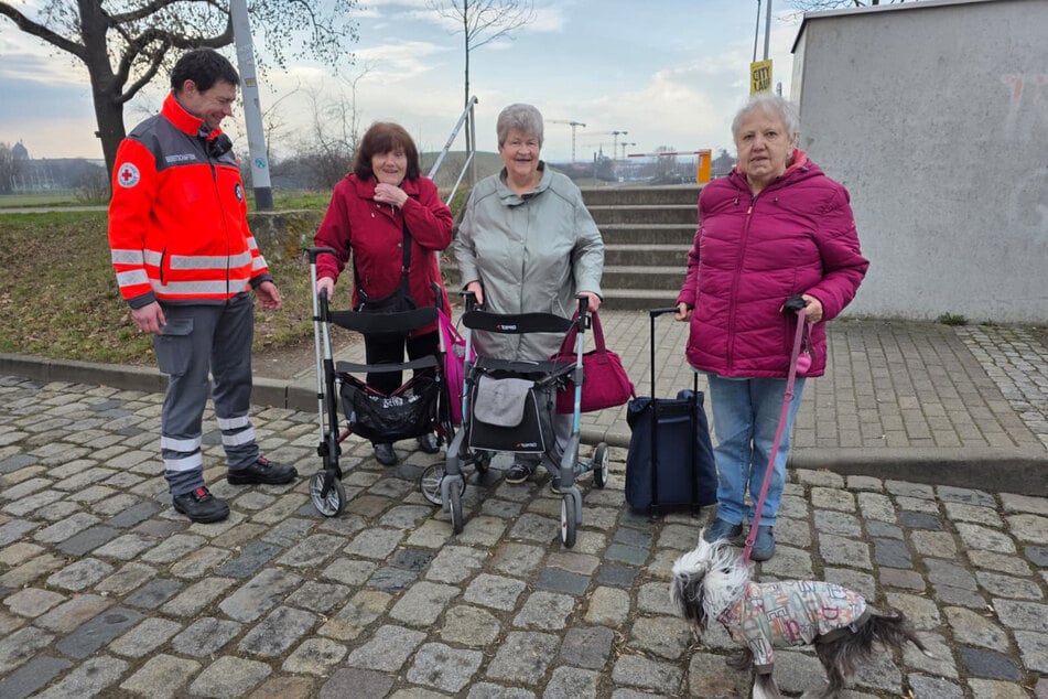 Drei Rentnerinnen, die per Straba von der Sarrasanistraße gekommen sind, werden von einem DRK Mitarbeiter zur Halle begleitet.