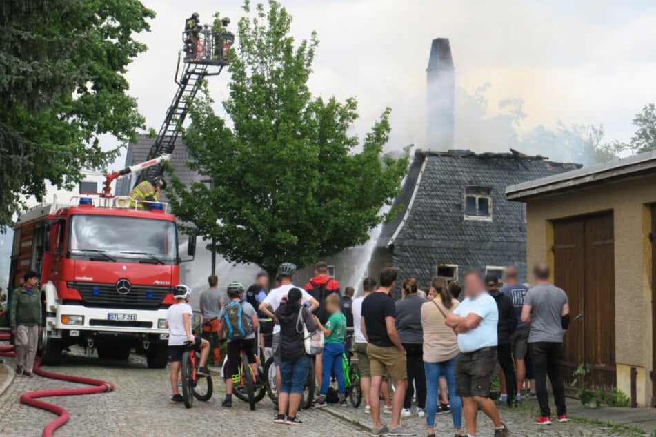 Mehrere Menschen sehen den Rettungskräften bei der Arbeit zu.