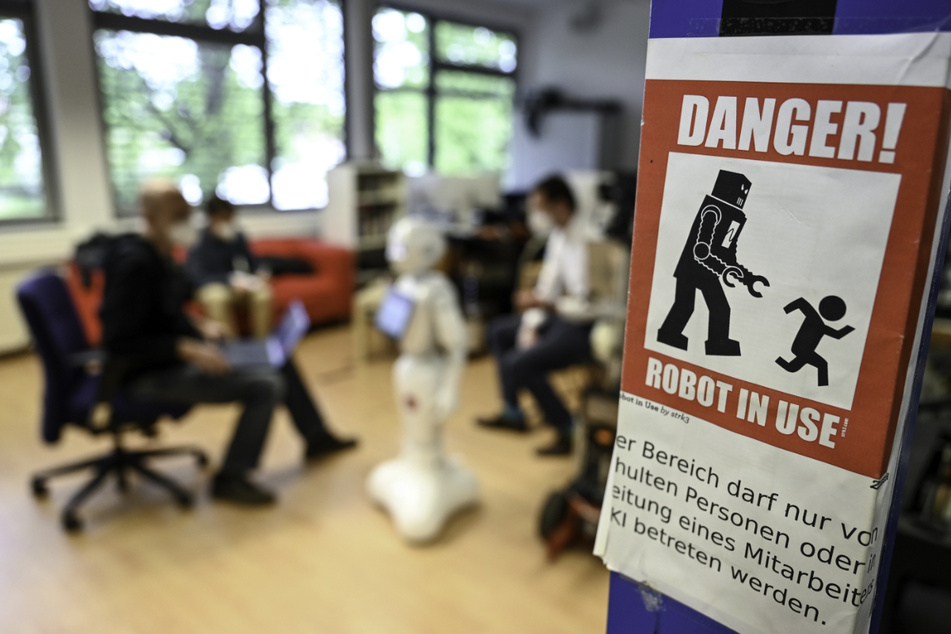 Ein Warnschild mit der Aufschrift "Danger! Robot in use" (dt. "Gefahr! Roboter in Betrieb") hängt an einem Pfeiler.