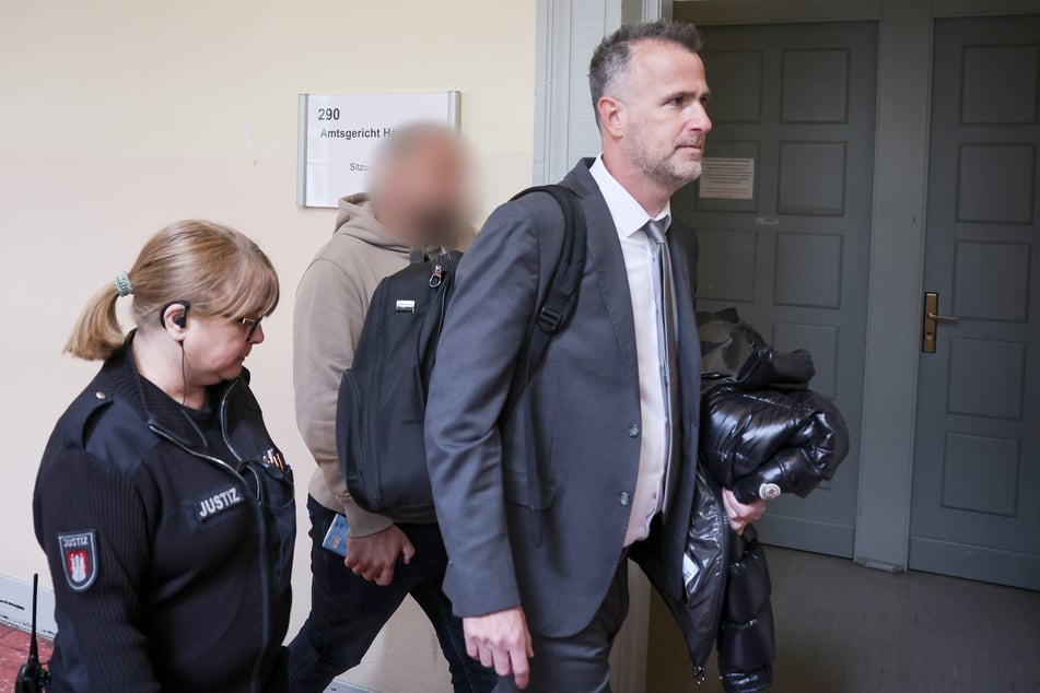 Der Zeuge B.mit seinem Anwalt Nir Yaslovitzh (r) und einer Justizbeamtin auf dem Weg zum Gerichtssaal im Strafjustizgebäude.