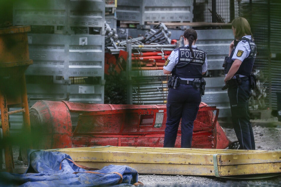 Einsatzkräfte der Polizei stehen auf der Hochbrücken-Baustelle neben der abgestürzten Gondel.