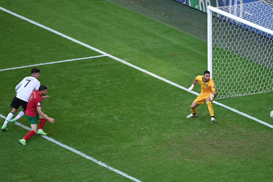 Ruben Dias (M.) gleicht - von Havertz (l.) bedrängt - zum 1:1 für Deutschland aus. Rui Patricio ist chancenlos.