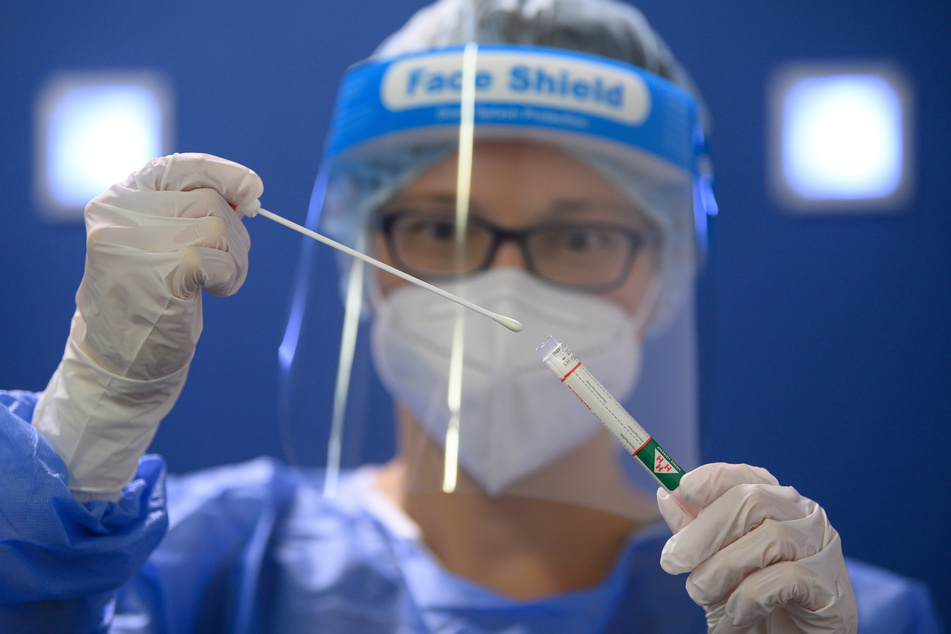 Eine Ärztin der Kassenärztlichen Vereinigung Sachsen hält in der Corona-Teststation für Urlaubsrückkehrer am Flughafen Dresden International einen Coronavirus-Test in den Händen.