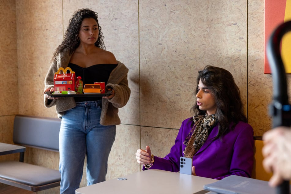 Daphne (25, l.) präsentiert die Pappschachteln des Folgen-Partners, während Alexavius (22) dieses Mal den Burger wohl lieber bekleidet zu sich nehmen möchte.