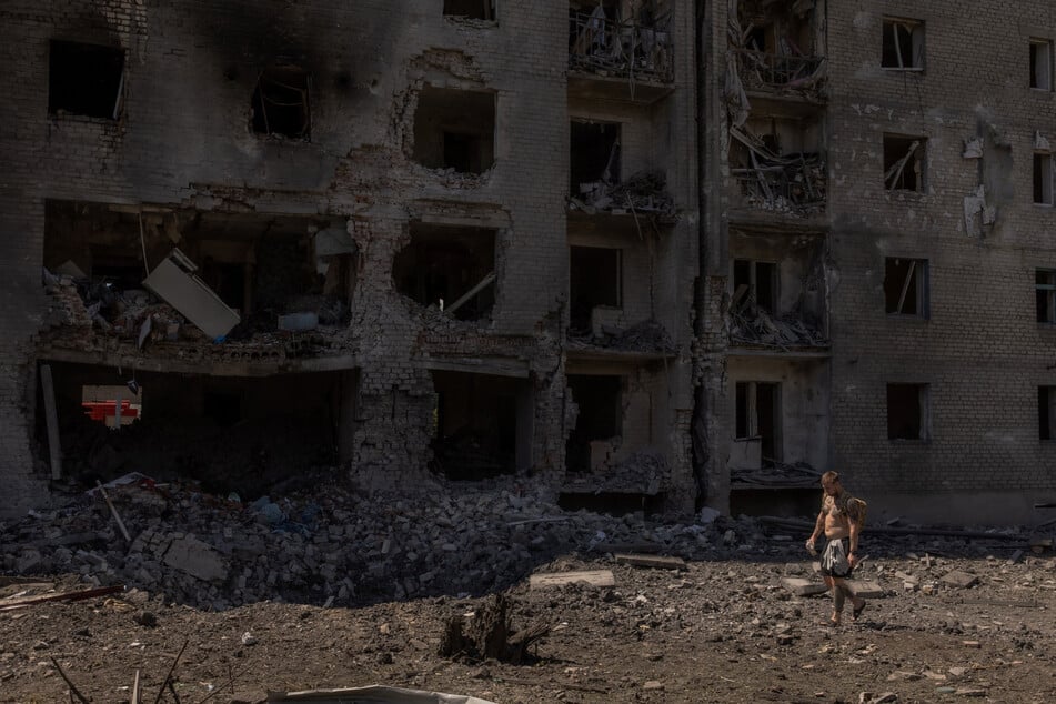 A man walks past a crater and heavily damaged apartment building following a Russian aerial attack, in Selydove, the eastern Donetsk region on June 27.