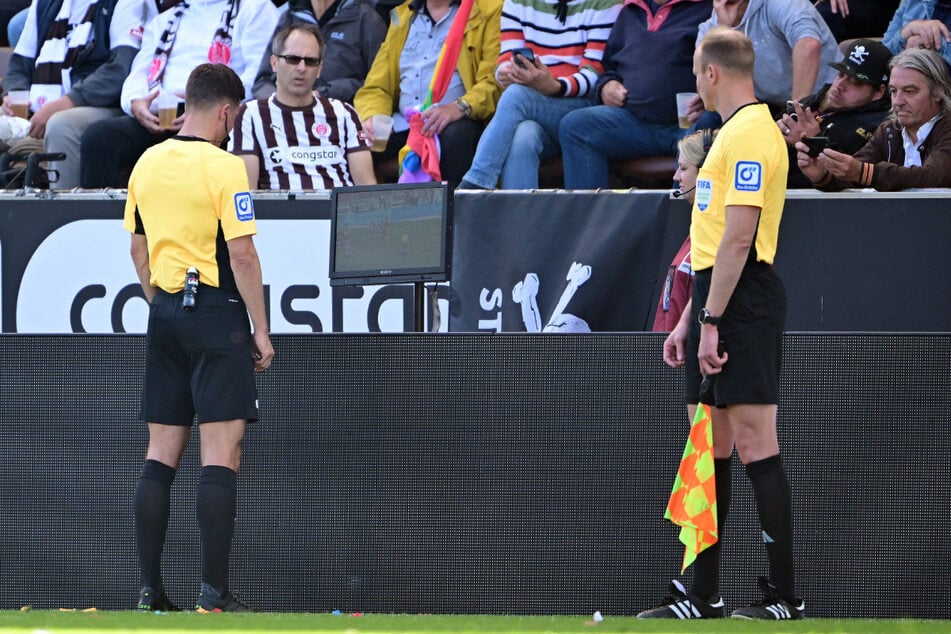 Schiedsrichter Harm Osmers (40, l) hatte eigentlich auf Handelfmeter entschieden, wurde aber vom VAR an den Bildschirm geschickt und revidierte seine Meinung.