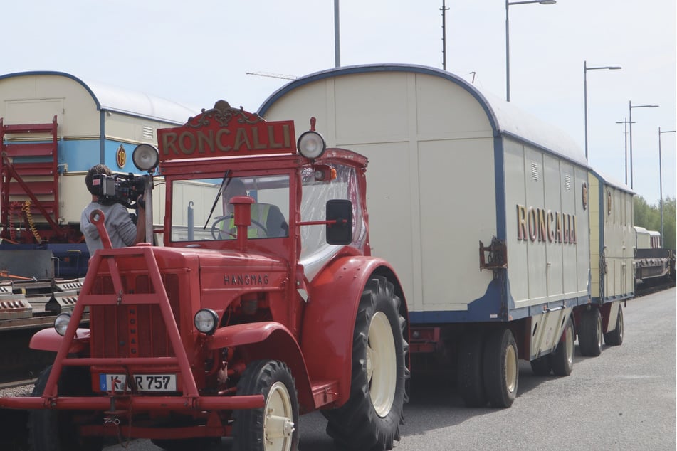 Verlademeister Steve Jones lädt mit dem roten Roncalli-Traktor die nostalgischen Zirkuswagen von den Schienen ab und fährt sie in Position.