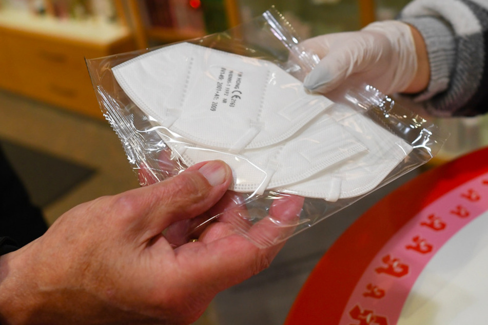 Eine Mitarbeiterin (r.) gibt in einer Apotheke FFP2 Masken an einen Kunden aus.