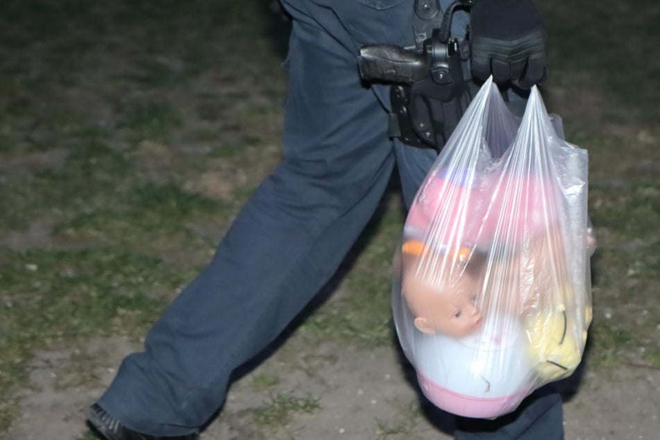Einsatzkräfte sammeln Stofftiere und Puppen auf, die das Kind offenbar aus dem Fenster geworfen hatte.