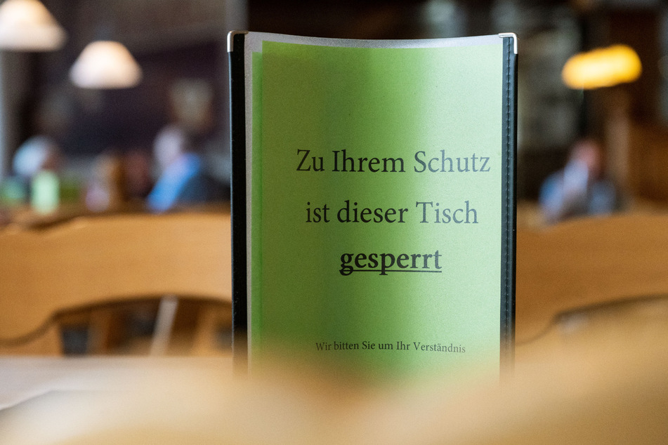 Ein Schild mit der Aufschrift "Zu Ihrem Schutz ist dieser Tisch gesperrt - Wir bitten Sie um Ihr Verständnis" steht in einer Gaststätte auf einem Tisch.