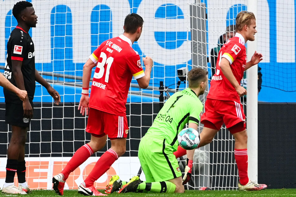 Nix zu halten für Leverkusens Keeper Lukas Hradecky (M). Unions Stürmer Joel Pohjanpalo (r.) bejubelt mit Robin Knoche (l.) sein Tor zum 1:1.