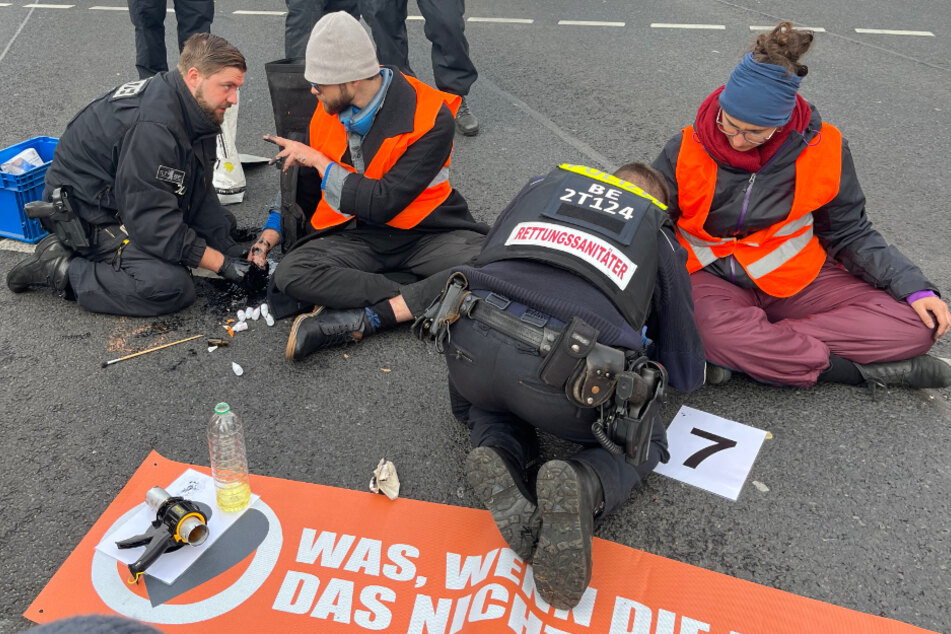 An der Kreuzung Frankfurter Allee/Möllendorffstraße kleben zwei Klimaaktivisten auf der Fahrbahn und blockieren den Verkehr.