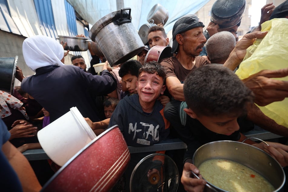 Palestinian children wait for food at a distribution point in Nuseirat, in the central Gaza Strip, on June 11, 2025.