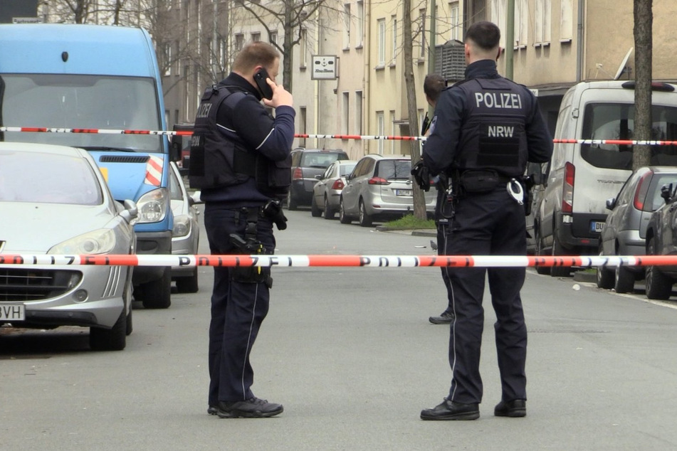 Zwei Beamte stehen an einem abgesperrten Tatort. In Duisburg sind zwei Kinder schwer verletzt worden.