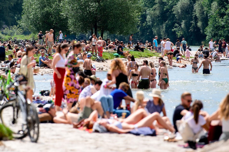Zahlreiche Menschen genießen das schöne und sonnige Wetter am Ufer der Isar.