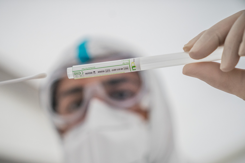 Ein Mitglied des medizinischen Personals steckt ein Wattestäbchen nach einem PCR-Abstrich zum Test auf Covid-19 in ein Röhrchen.